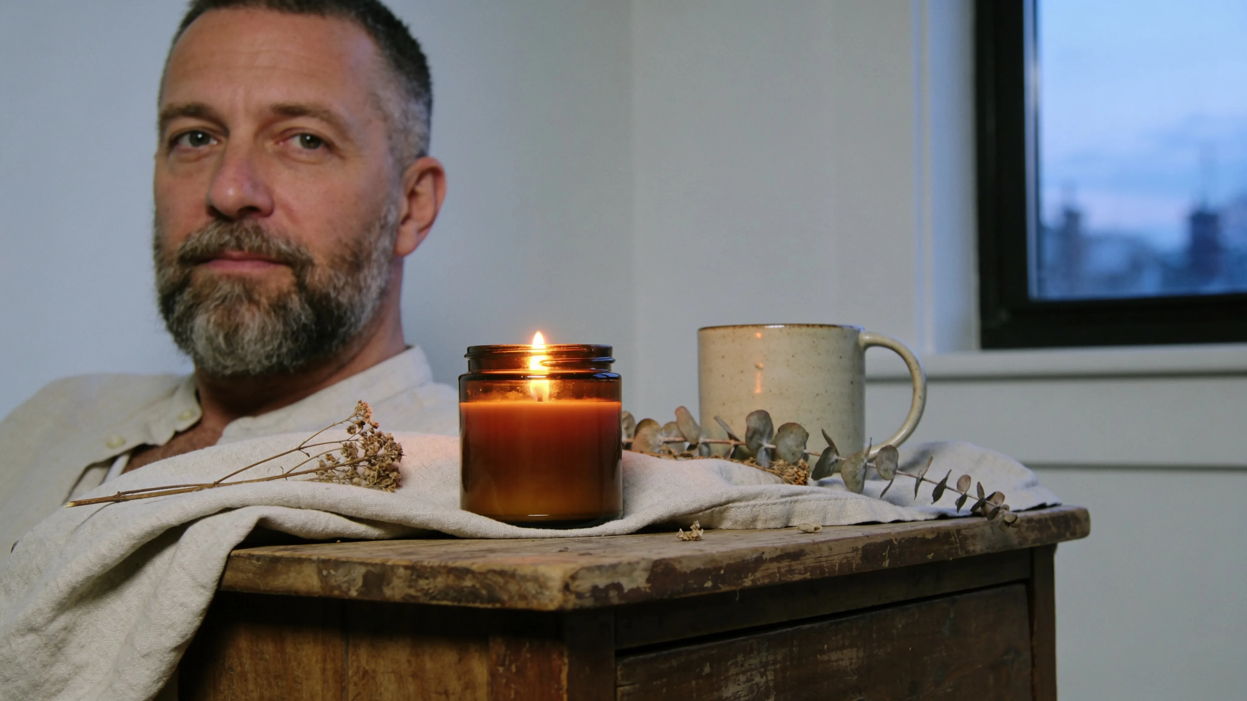 Hand pouring melted soy wax into a glass candle vessel in small batch
